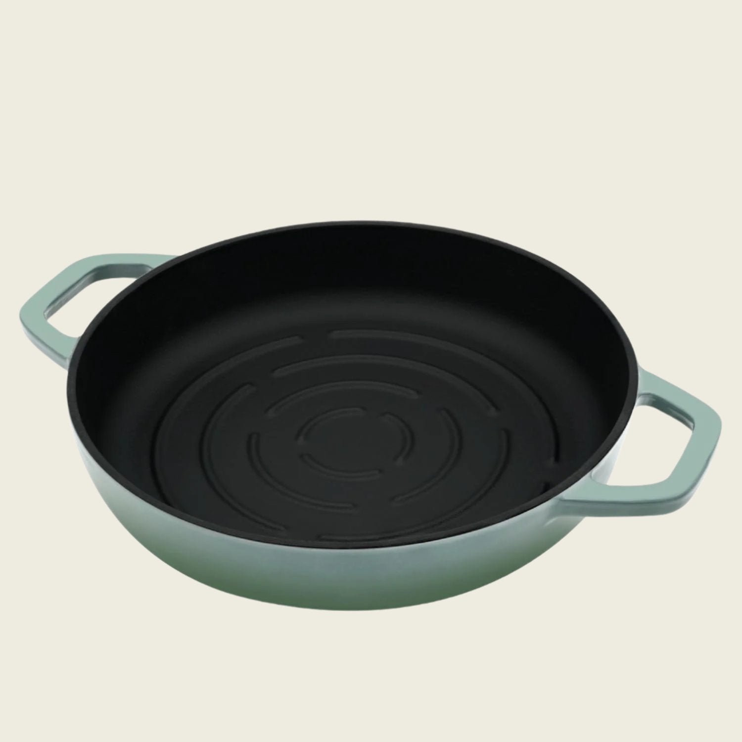 Green cast iron bread pan with black interior on a beige background