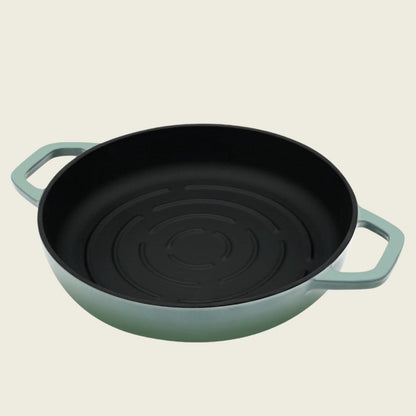 Green cast iron bread pan with black interior on a beige background