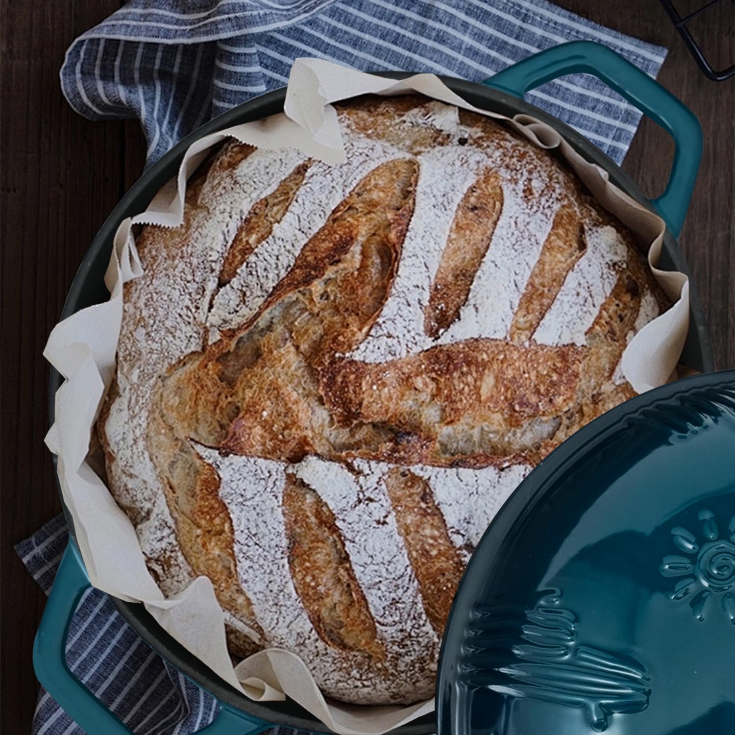 Baked bread in a round baking dish with a blue lid on a wooden surface.