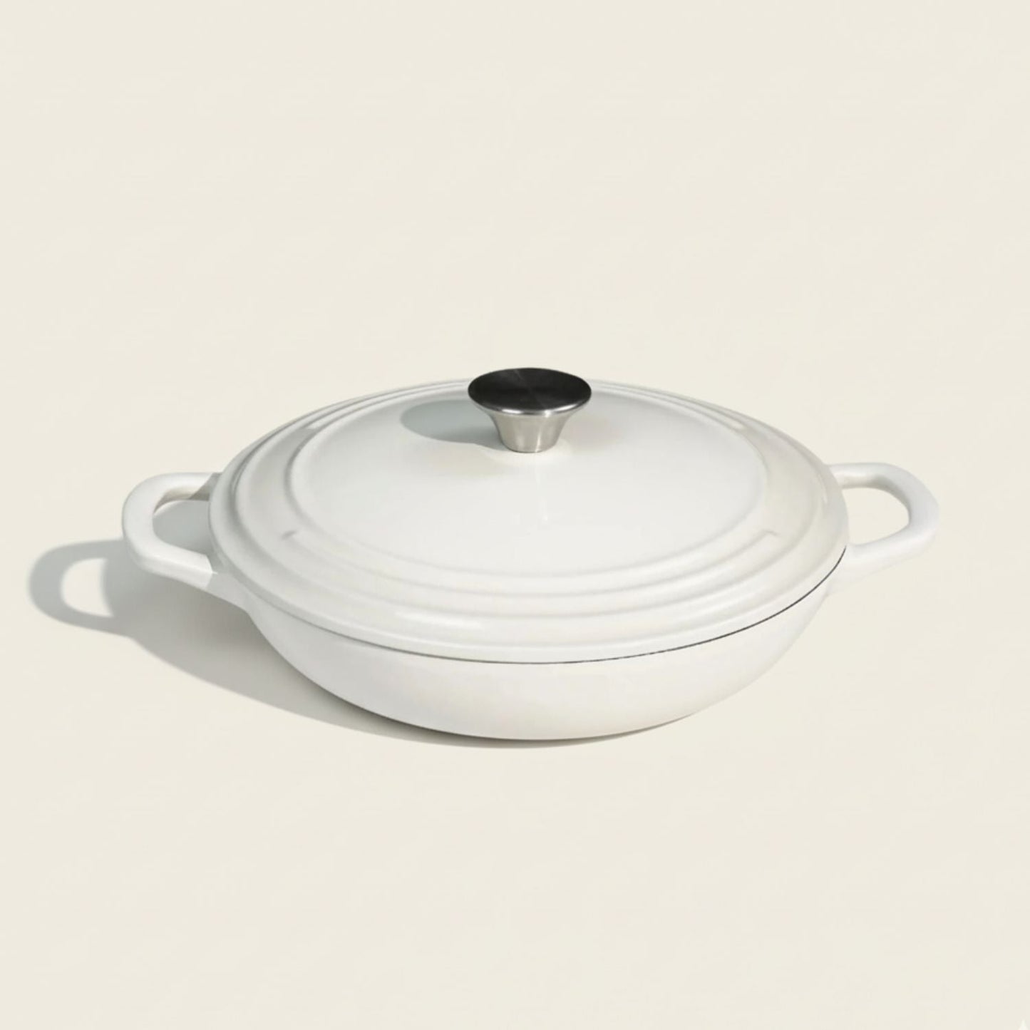White enameled cast iron casserole dish with a lid on a beige background