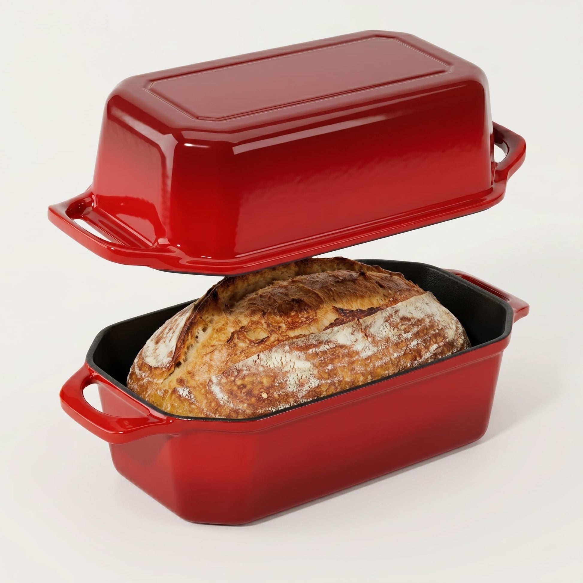 Red enameled cast iron bread loaf pan with a loaf of bread inside on a white background