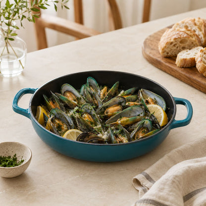 dark cyan enamelled cast iron shallow casserole with black interior and side handles, mussels with lemon