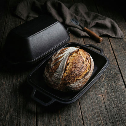Oval bread oven open with baked loaf, lid set beside it Black (Pre-Seasoned)