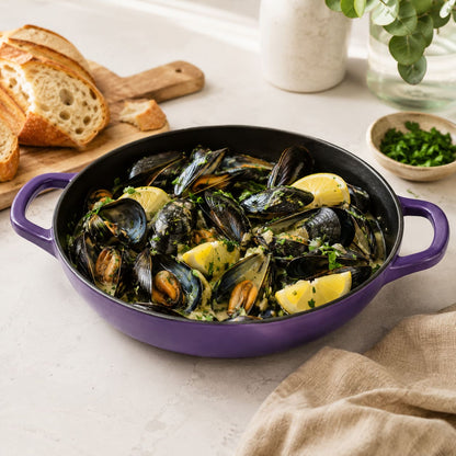 Iris purple enamelled cast iron shallow casserole with side handles, filled with mussels