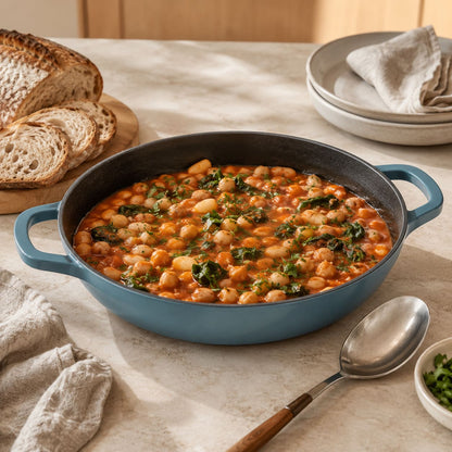slate blue enamelled cast iron shallow casserole with two side handles, filled with soup