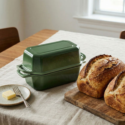 Green cast iron bread loaf pan set on a table with bread and butter