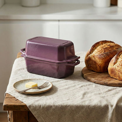 Purple cast iron bread pan on a kitchen counter with bread and butter.