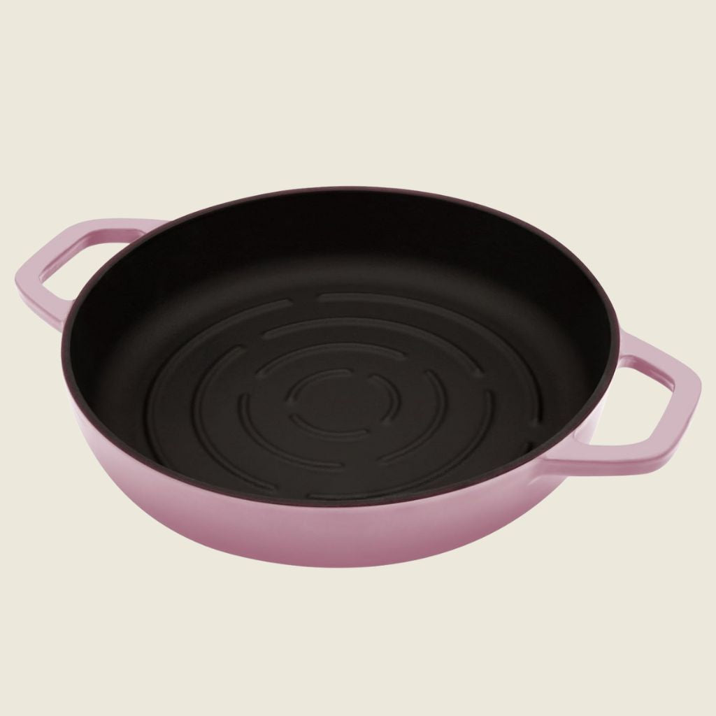 Black cast iron bread baker with pink handles on a beige background