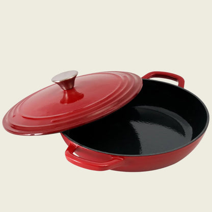 Red enameled cast iron shallow casserole dish with lid on a beige background
