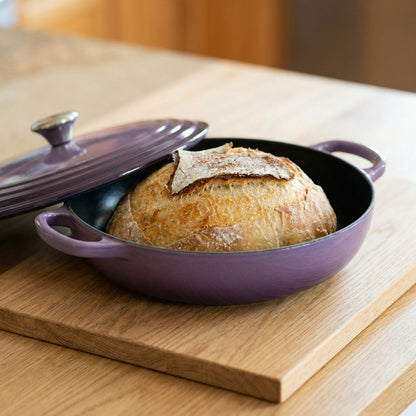 Baked bread in a purple baking dish on a wooden surface