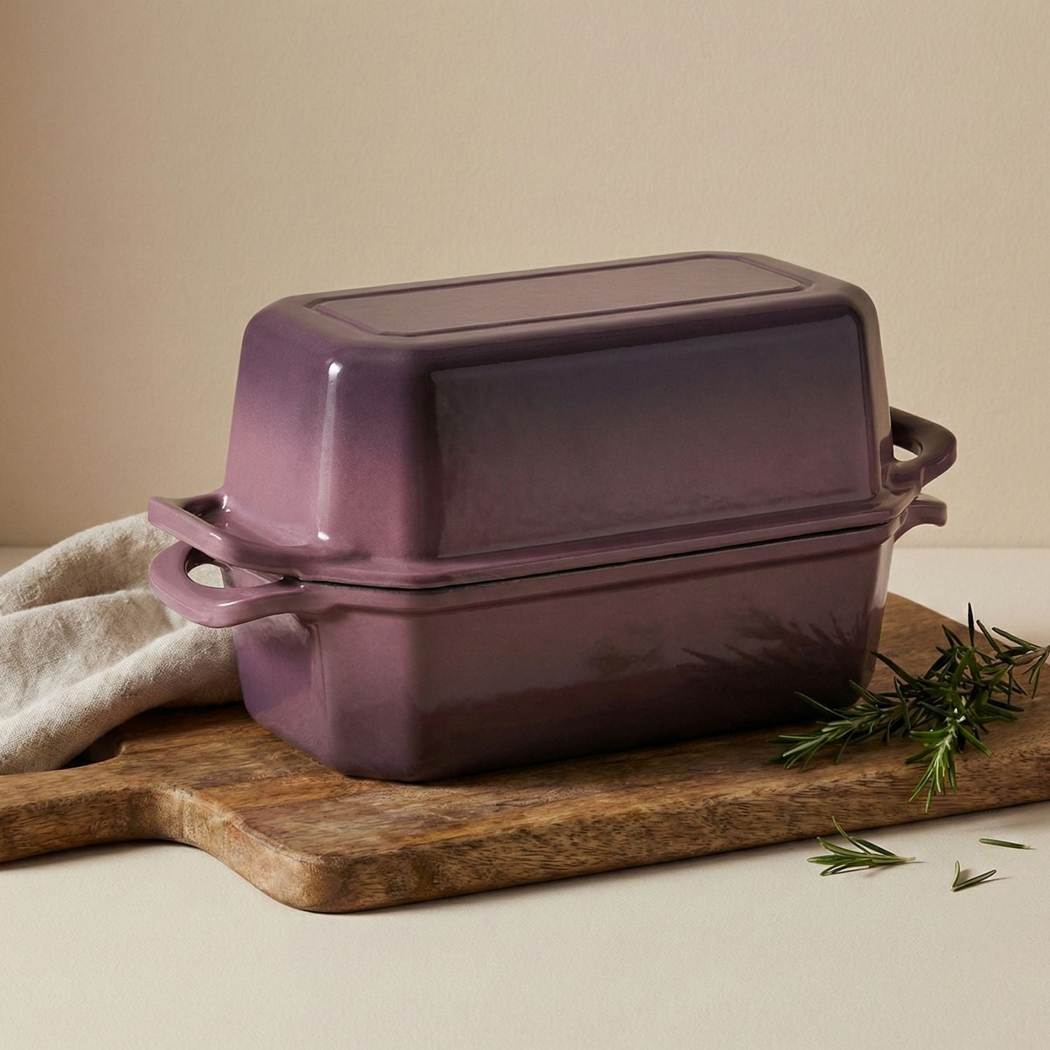 Purple rectangular baking dish bread loaf pan on a wooden cutting board with a beige background